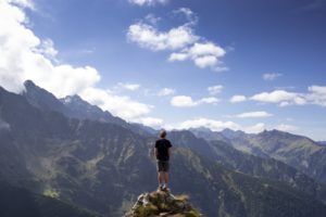 Un homme en haut d'une montagne contemple l'ohrizon